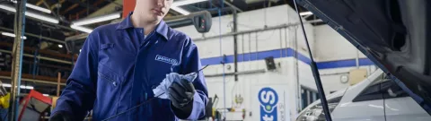 Un tecnico di Point S mentre esegue il tagliando di un’auto, controllando l’olio motore e i livelli dei liquidi