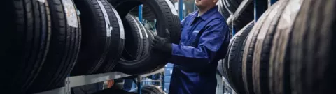 Un tecnico di Point S che tiene uno pneumatico tra due supporti per pneumatici per verificarne l'indice di velocità
