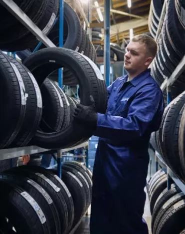 Un tecnico di Point S che tiene uno pneumatico tra due supporti per pneumatici per verificarne l'indice di velocità
